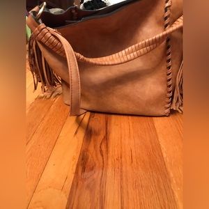 Tan faux leather purse with braiding and tassel details.